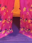 Kid's play tent with purple floor and orange walls with pink patterened doors partly open