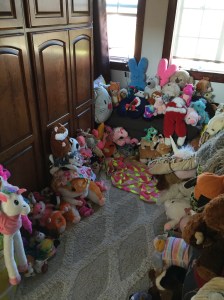 Kids stuffed animal museum display with critters sitting on floor, chaise lounge sofa, bed, rug and more covered with toys