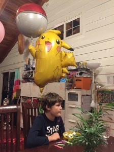 Pikachu and Poke ball balloons tied to chair with child sitting underneath