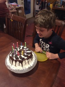 Ten year old boy blowing out birthday candles on mint chocolate chip homemade ice cream cake