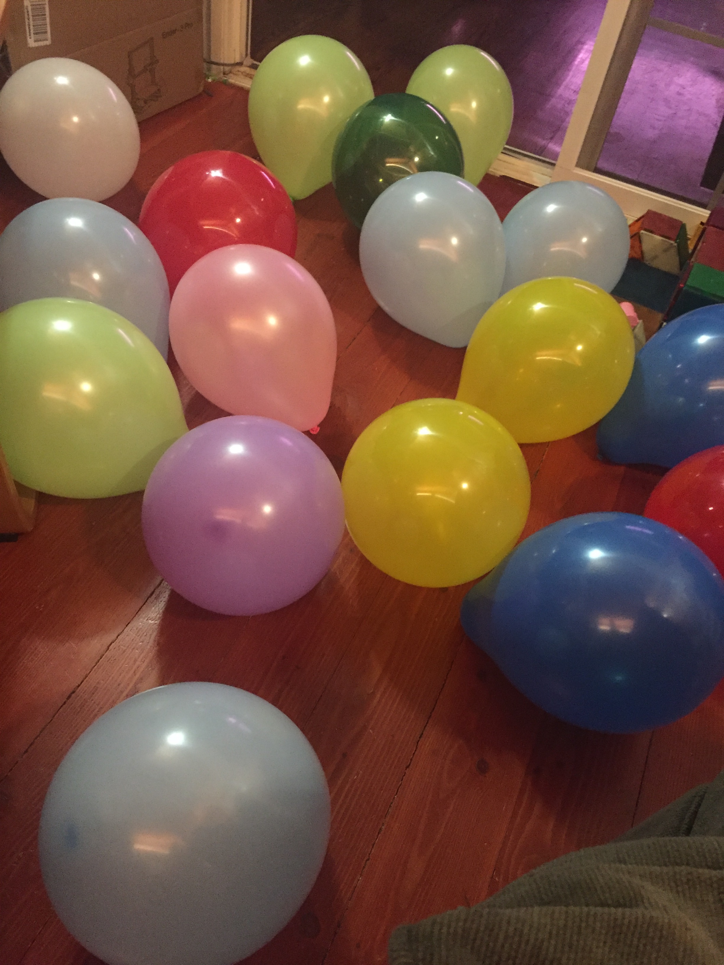 Birthday balloons inflated and scattered over hardwood floor