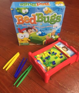 Bed Bugs game by Hasbro set up with tweezers beside and box behind bed