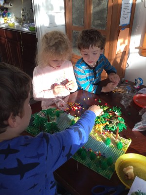 Child adding pieces to jungle forest garden park building brick play set