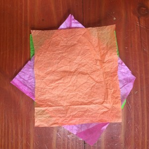 Tissue paper in pink, green, and orange stacked 90 degrees offset on each layer