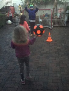 Kids playing with glowcity light up soccer ball in black and orange on brick patio at dusk