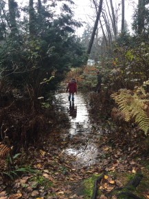 Girl wearing Mymayu Traveler rain boots for kids in giant puddle in the woods