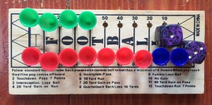 Football peg game with green blue and red pegs inserted into wooden board and two purple dice