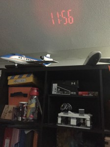 Capella projection alarm clock time displayed on white ceiling over cubby shelves