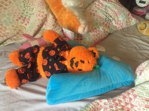 iscream Lettermania V shaped pillow on child's bed with Build a Bear orange bear in pumpkin pajamas laying on it