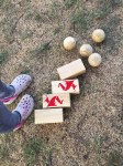 Kingdoms Lawn game red blocks castles and wooden balls armies next to child's feet on grass