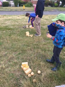 Kids and grown up playing Kingdoms lawn game on grass in park next to road
