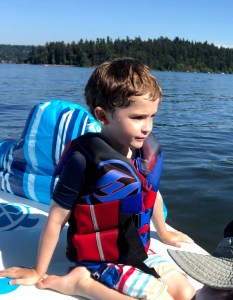 Child wearing life jacket on board boat float raft on lake