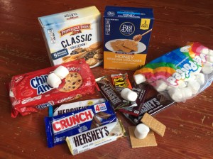 Deluxe s'mores ingredients laid out Chips Ahoy chocolate chip cookies graham crackers marshmallows Pepperidge Farm cookie assortment Nestle Crunch candy bar Hershey's chocolate candy bars