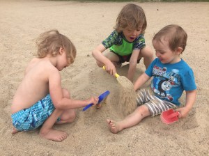 Three kids digging in sand and burying each other in Boise, ID