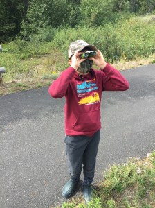 Ten year old child using Obuby binoculars on paved trail