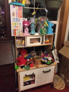 IKEA play kitchen mess with pretend food dishes and more piled precariously