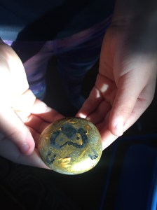 Child holding painted rock made from rock painting kit in hands
