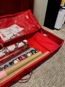 Wrapping paper organizer open and unzipped showing rolls of paper and supplies like tape and scissors