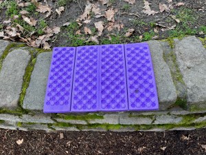 Folding foam seat pad camping outdoor kids insulated weatherproof foam mat in purple on stone wall