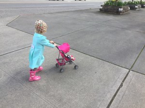 Young child pushing Mommy and Me My First Baby Doll Stroller on sidewalk
