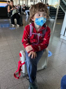 Seven year old boy using JetKids BedBox as a seat at an airport gate