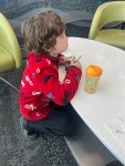 Seven year old in airport lounge with Nuk Hard Spout Sippy cup in orange with polka dots