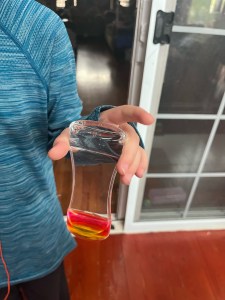 Child holding Super Z Outlet Liquid Motion Bubbler sensory toy with pink and yellow liquid bubbles