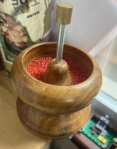 Bead spinner bowl loaded with tiny pink iridescent seed beads