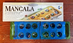 Mancala game board painted by seven year old child next to game box