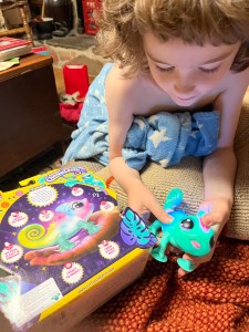 Seven year old child petting Little Live Pets Sunny the Chameleon toy