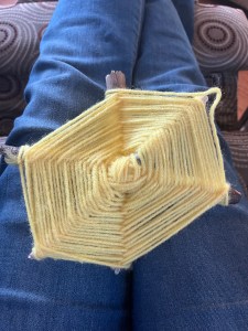 God's eye weaving yellow yarn spider web made by seven year old