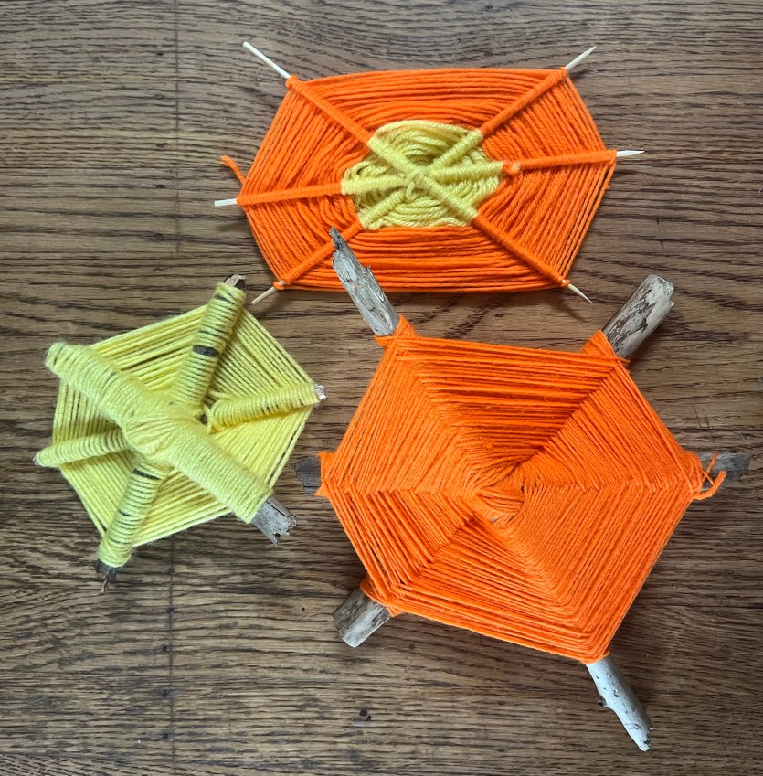 God's eye weavings yarn webs in orange and yellow crafted by seven year old kid