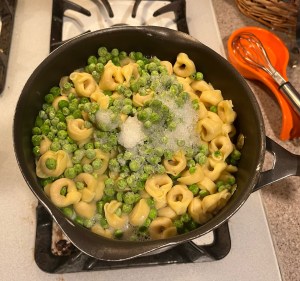 Frozen peas added to pot of Barilla Three Cheese Tortellini cooking on stove