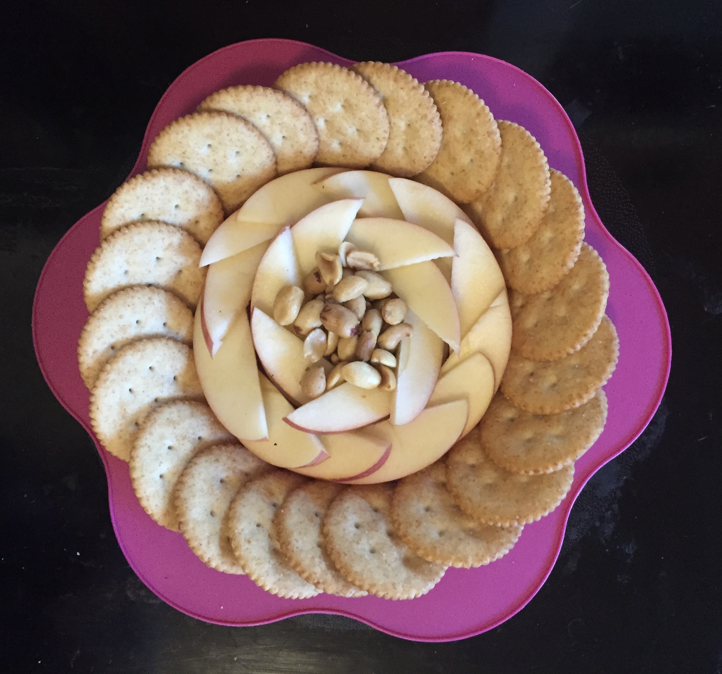 Snack plate for kids on pink flower plate with Ritz crackers, apple sli s, and