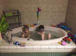 Two kids in goggles in big garden bathtub taking a bath