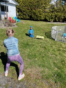 Kids playing Toss Across lawn game outside in grass