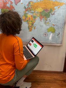 12 year old boy playing Worldle on computer with laminated map