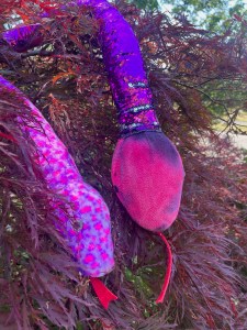 Pink stuffed snake animals in Japanese maple tree