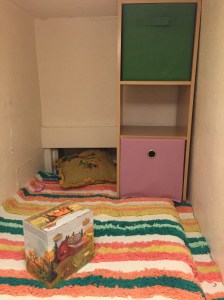 Nook play area for kids in closet with rug, pack and play crib mattress, and cube shelves with bins