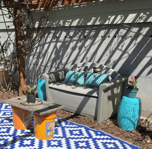 Pillow Perfect Hockley Teal lumbar pillows on plastic outdoor storage bench