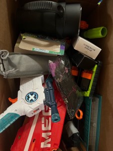 Pile of items to donate in cardboard box Nerf guns