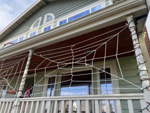 Rope spider web Halloween decorations strung between porch columns on house