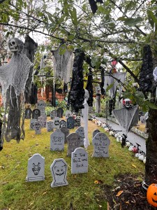 Front yard decorated for Halloween with tombstones, ghouls hanging from branches, and skulls lining walkway