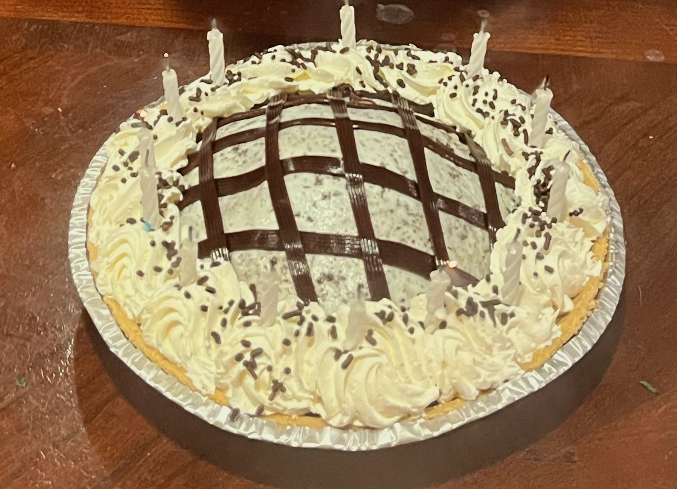 Mint chocolate chip ice cream pie with birthday candles around the edges
