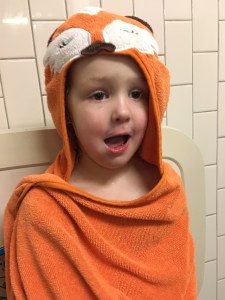 Child wearing fox hooded towel in bathroom