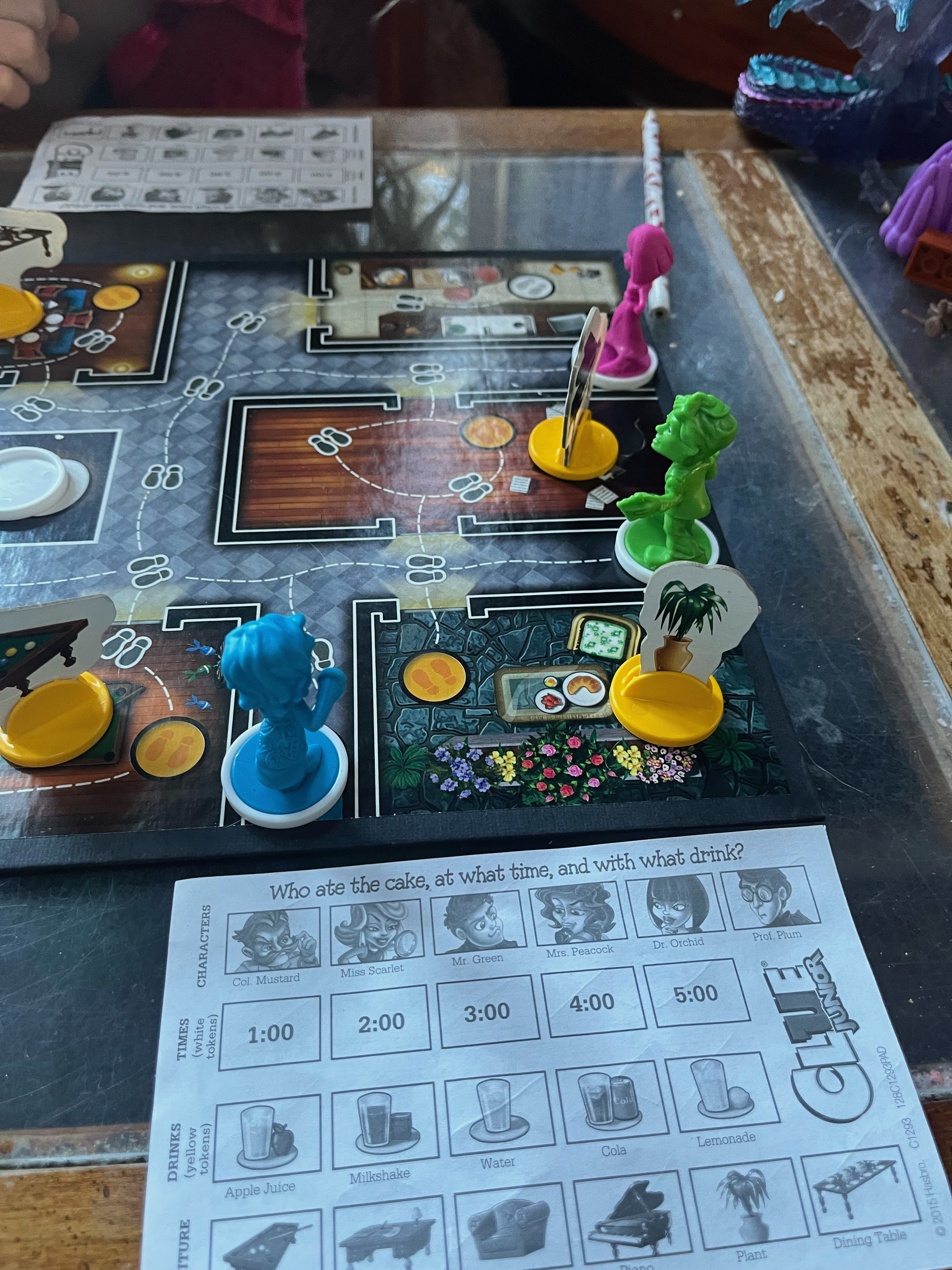 Clue Junior board game with brightly colored pawns set up and pictorial clue sheet next to game board