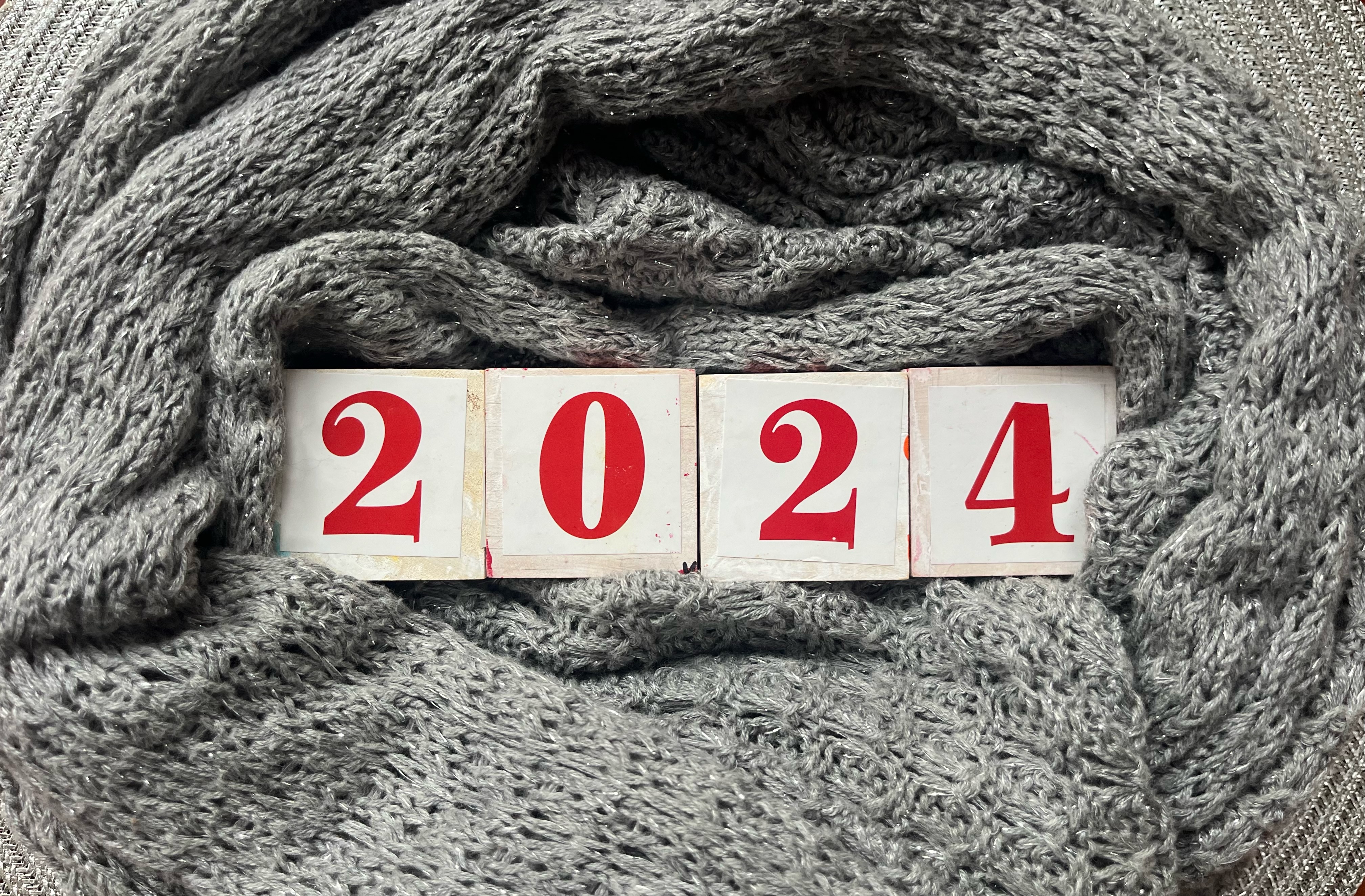 2024 number in white wooden blocks with red number stickers surrounded by sparkly silver fabric in circle