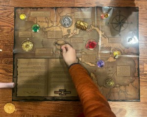 Nine year old placing gem on treasure map from MindWare's Dig It Up Giant Pirate Discovery activity kit