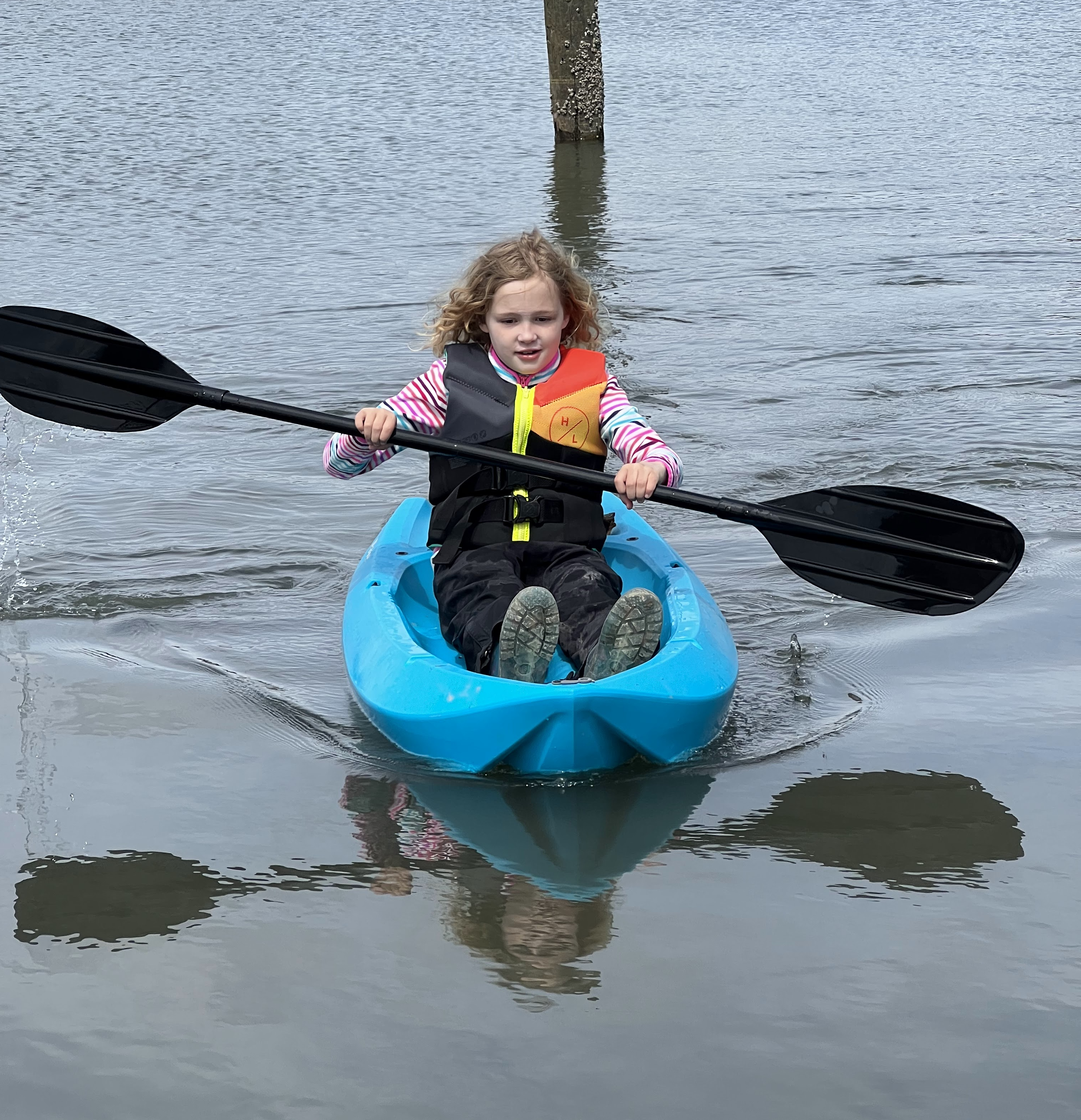 Child with black paddle kayaking in blue