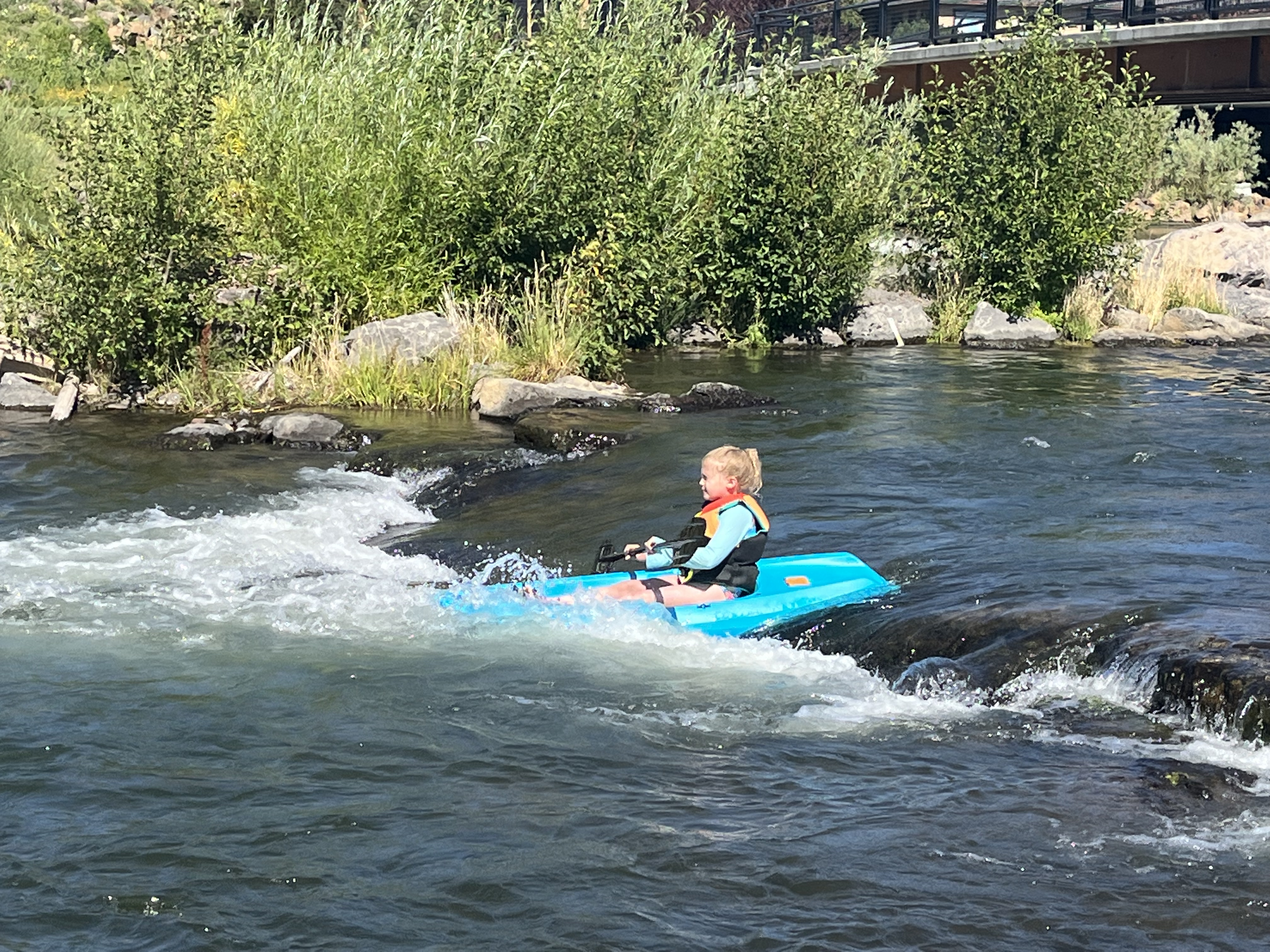 Girl kayaking small rapid in bright blue Lifetime Wave kids kayak